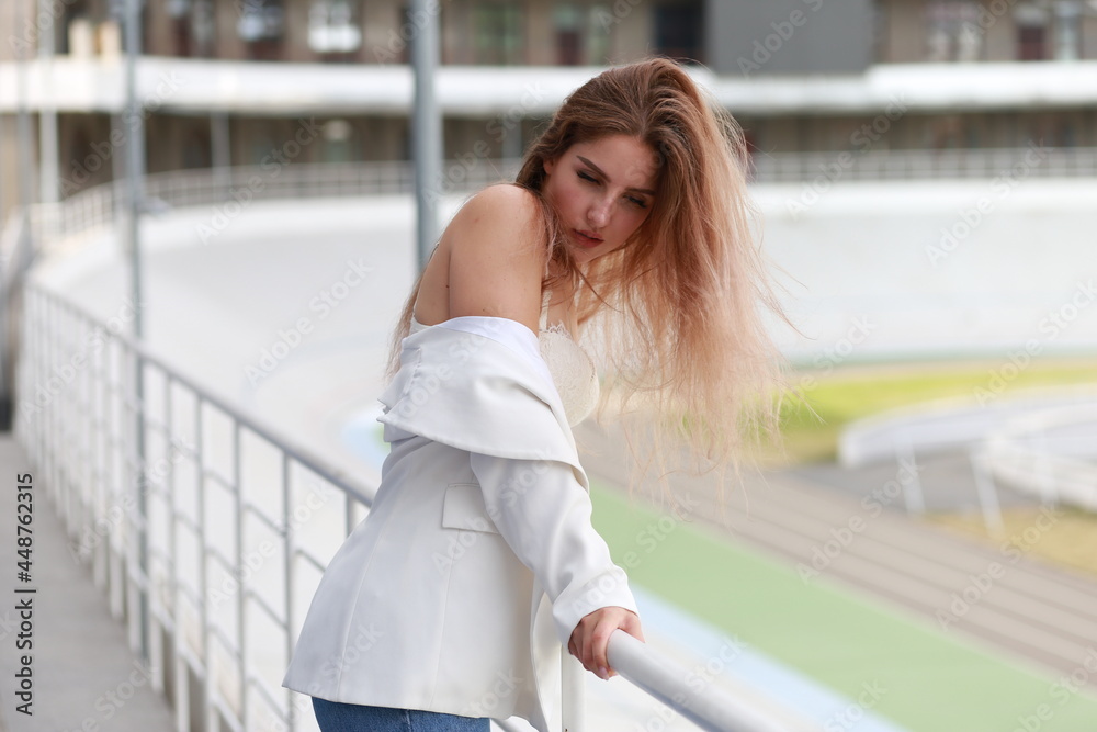 Young sensual fair-haired woman near metal railing at stadium Young sensual fair-haired woman near metal railing at stadium