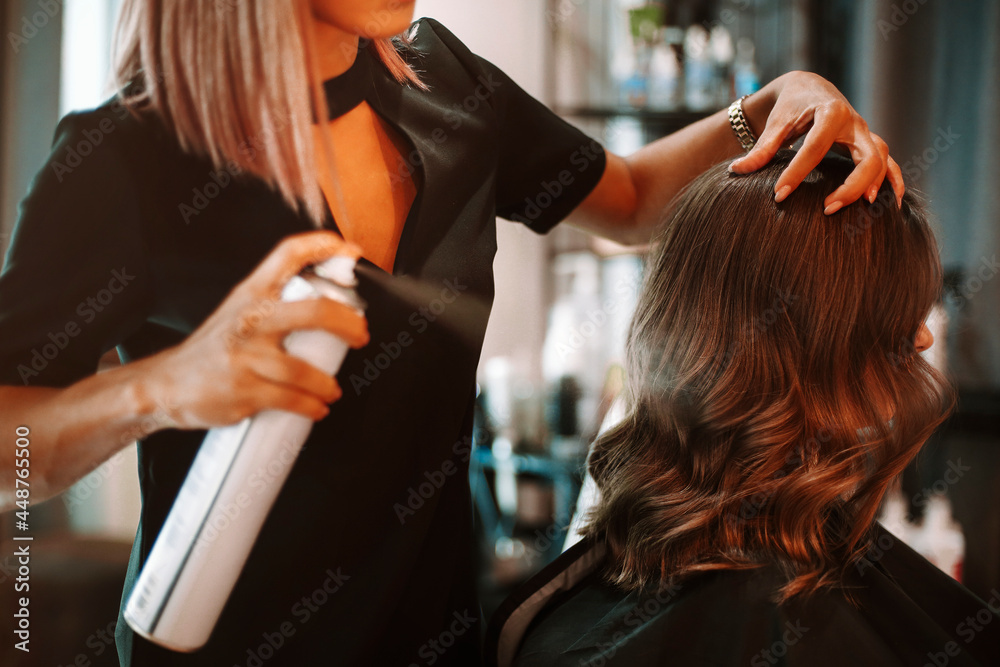 Female hairdresser fixing customer woman hair with spray and put care  treatment while styling curls Stock Photo | Adobe Stock