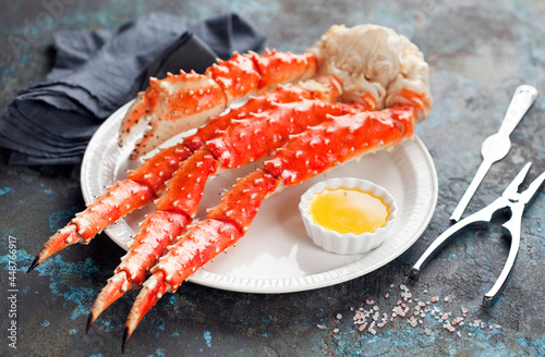 Red king crab legs with butter sauce on a plate, selective focus