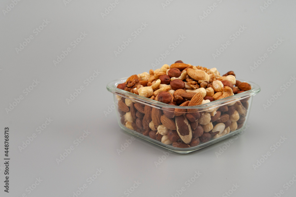 assorted nuts in a glass plate on a gray background
