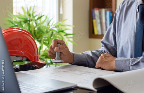 Architect man or male engineer hand stamping rubber stamper on  blueprint paperwork at office. Authorized allowance permission approval concept.