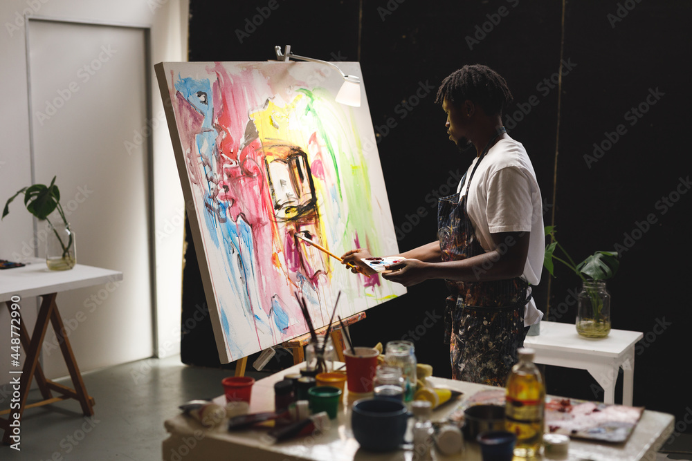 Obraz premium African american male painter at work painting on canvas in art studio