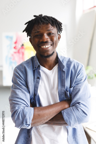 Portrait of smiling african american male painter at work looking at camera in art studio photo