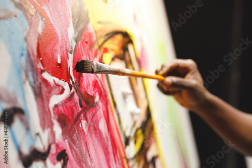 Close up of african american male painter at work painting on canvas in art studio