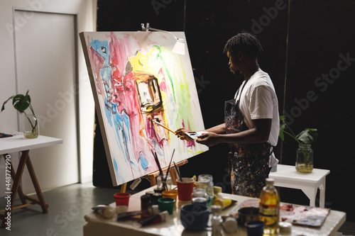 African american male painter at work painting on canvas in art studio