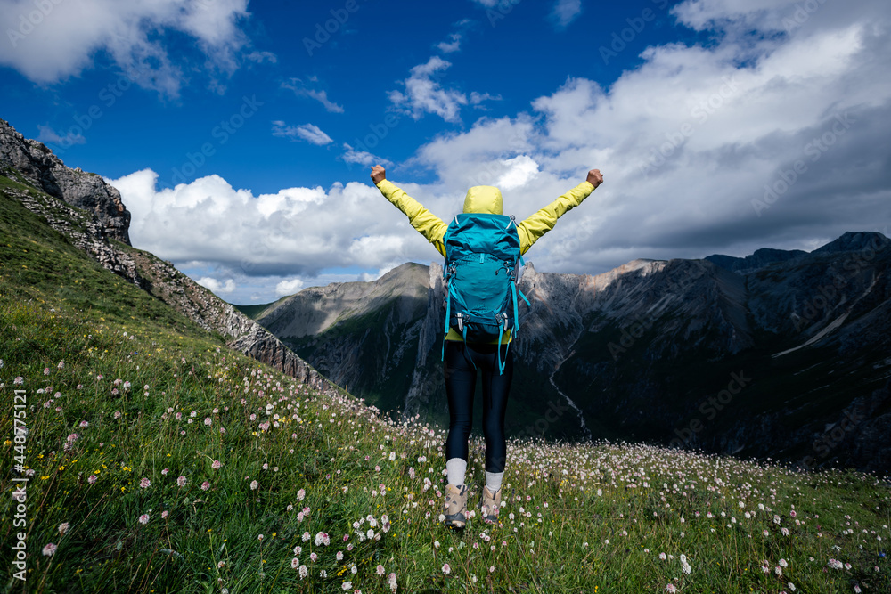 Successful woman backpacker hiking on alpine mountain peak