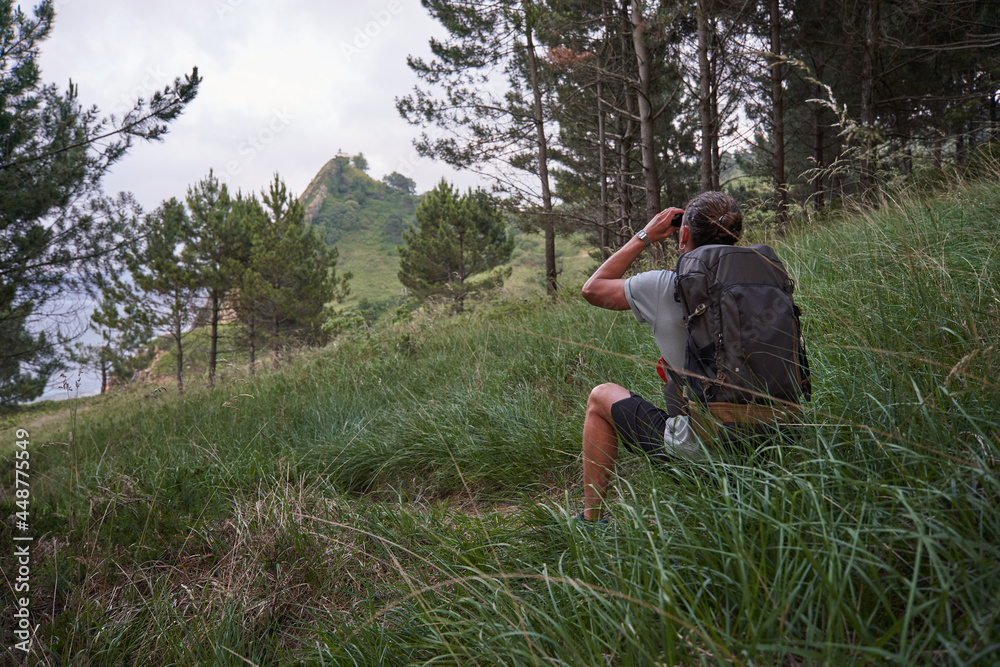 Unrecognizable hiker observing mountain in binoculars Unrecognizable hiker observing mountain in binoculars