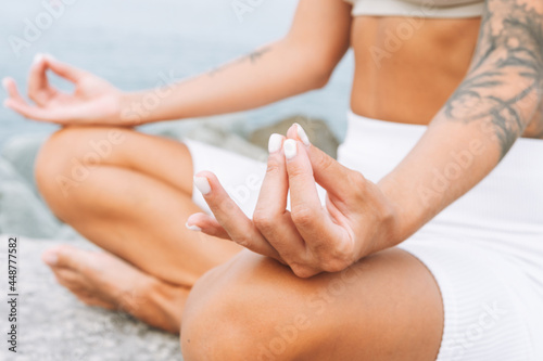 Crop photo of young fit beautiful woman with long hair in white sport clothes practice yoga and enjoy life on the sea beach, mental and phisical health