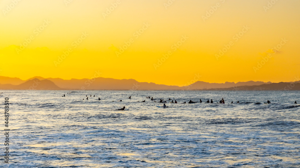 Surfers waiting for the perfect wave with the mountains in the background.