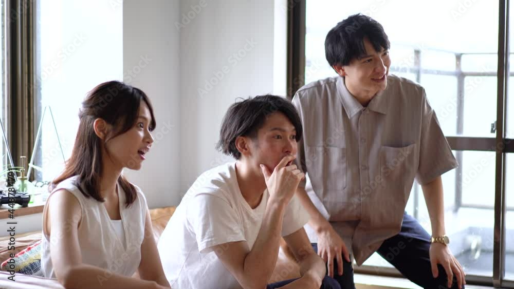 おうちでスポーツを観戦する若い男女