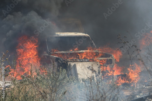 Burning car in a field covered by fire