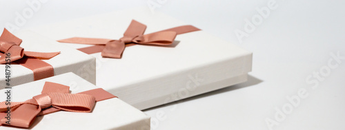 three white gift boxes with pink satin bow on white background,