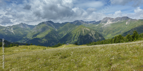 Panoramabild einer Berglandschaft mit Wollgras und einer Almh  tte kurz vor einem Gewitter