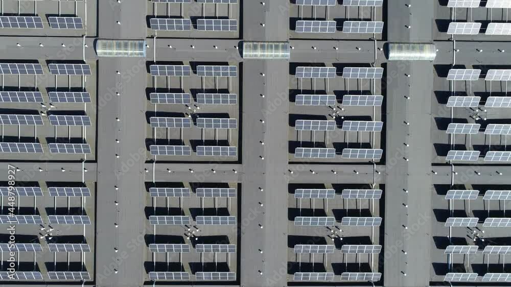 Aerial view of solar energy panels on a roof of a building. Power plant of photovoltaic, solar cell farm power plant. Concept of sustainable resources and alternative electricity source. Aerial view of solar energy panels on a roof of a building. Power plant of photovoltaic, solar cell farm power plant. Concept of sustainable resources and alternative electricity source.