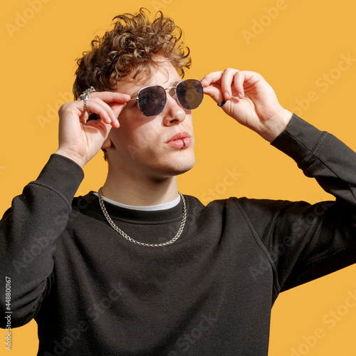 portrait of an epic man in sunglasses. studio photo yellow background