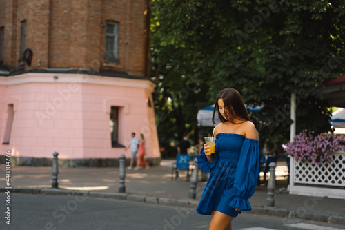 Portrait happy young woman wearing blue dress and drinking summer cocktail lemonade