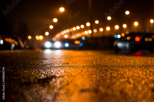 City night lights, road bridge with the lights and moving cars in the fog after rain. View from the level of asphalt