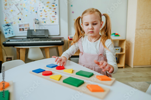 Adorable preschool student sorting wooden geometric forms
