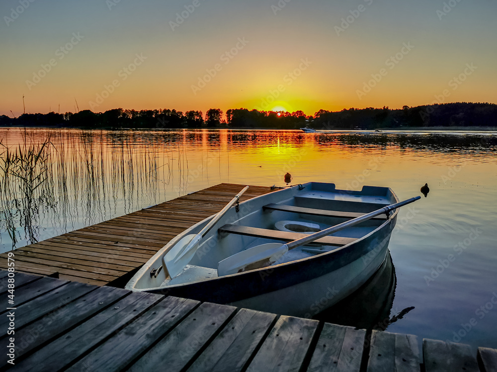 Photo of an empty boat at the pier in the lake at sunset in summer