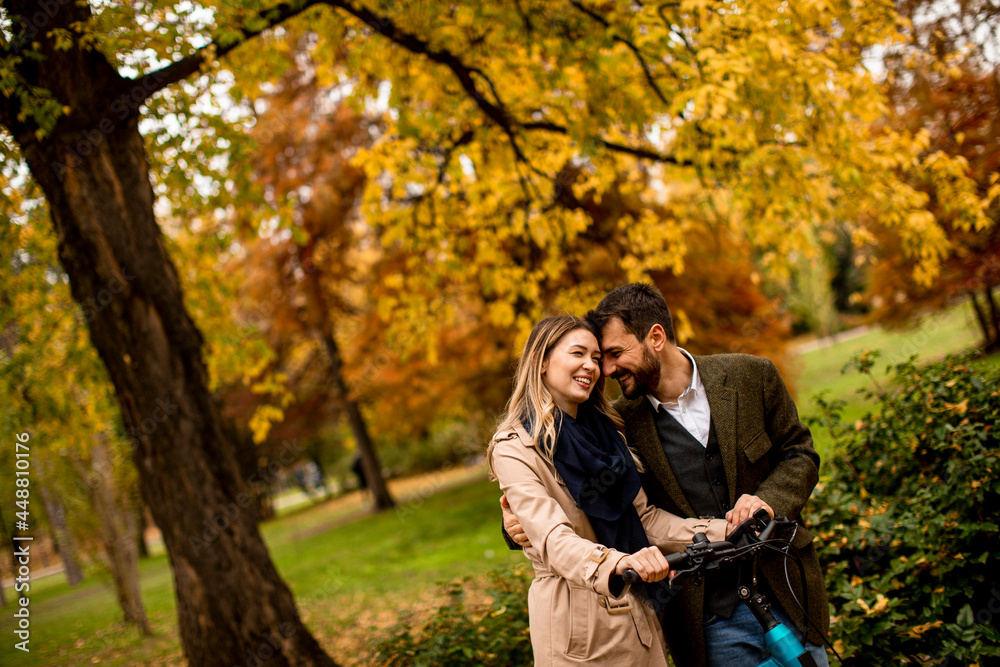 Young couple in the autumn park with electrical bicycle Young couple in the autumn park with electrical bicycle