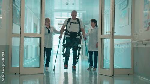 A man in the exosuit is walking with doctors' aid photo