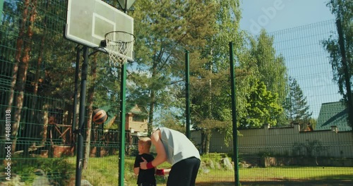 Basketball players sport family father and son on basketball court. Dad helping kid scoring hoop raising up boy on hands
