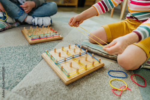 Preschool students playing with geoboard wrapping rubber bands in kindergarten photo