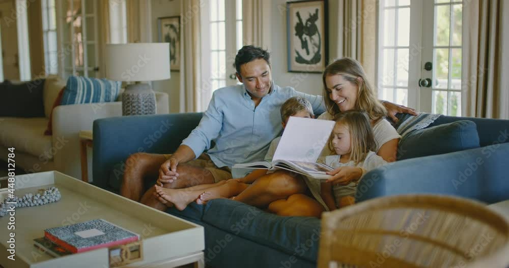 Happy young diverse family relaxing at home in the living room playing board games and reading book, family lifestyle