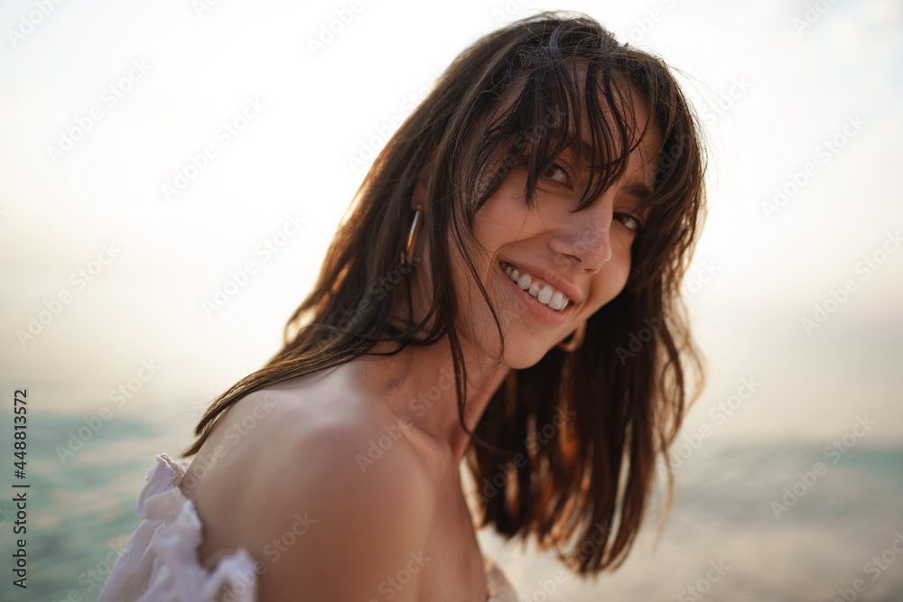 Portrait of young brunette haired woman at the beach at sunset