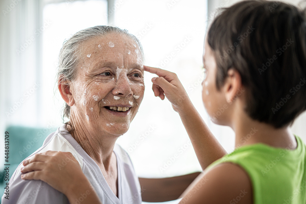 Fototapeta premium Grandmother and little boy putting cream protection on their face