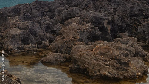 Detailed view of volcanic coastline with high cliffs and waves breaking over volcanic rocks, Portugal.