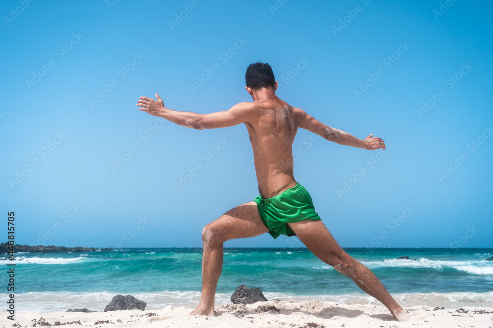 young man does stretching on the shore of the beach. Orzola. Lanzarote. Canary Islands