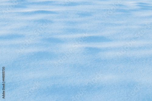 Snowy background, snowy surface with a clearly expressed texture of snow in the morning sun