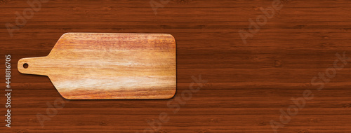 Wooden cutting board isolated on dark wood background. Horizontal banner