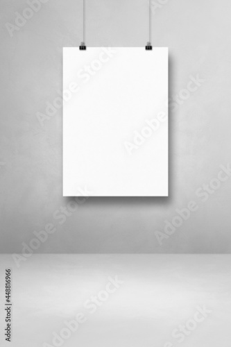 White poster hanging on a light concrete wall with clips