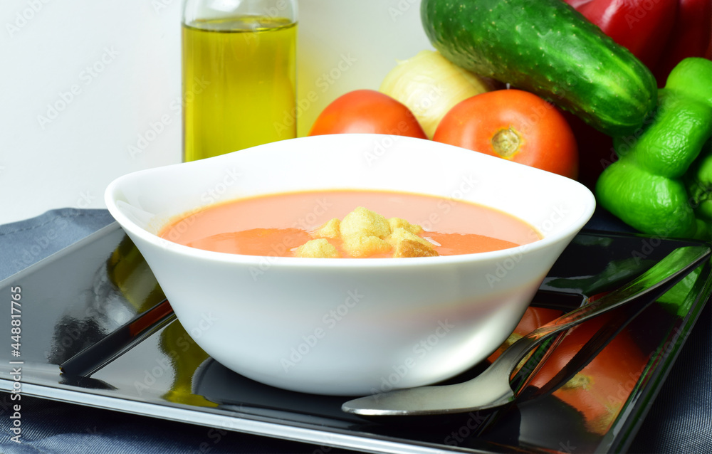 Andalusian homemade gazpacho, from Spain, served on a white plate with breads and exposed with its ingredients. Healthy and beneficial Andalusian homemade gazpacho, from Spain, served on a white plate with breads and exposed with its ingredients. Healthy and beneficial