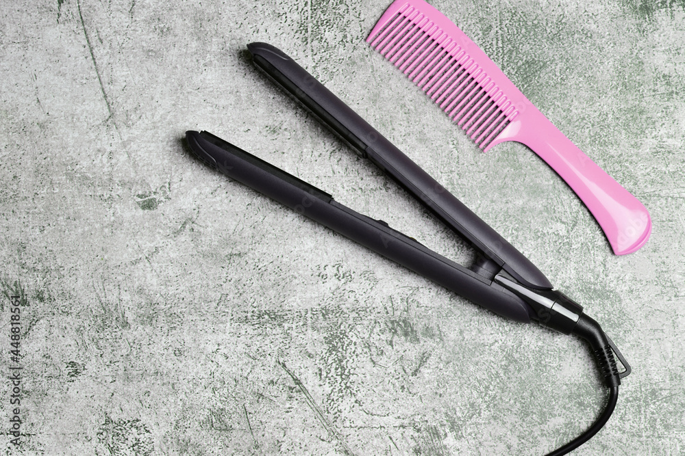 Hair straightener with isolated ceramic plates together with a long comb, on a stone background. Copy space. Hair straightener with isolated ceramic plates together with a long comb, on a stone background. Copy space.