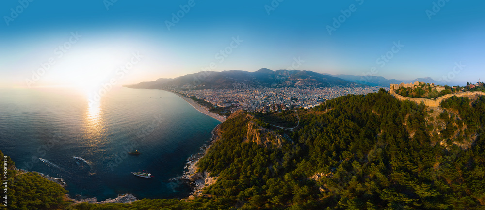 Large panorama. Wide aerial view from Kalesi Castle peninsula. Alanya, southern coast of Turkey, Summer sunset. Travel and vacation. Ships and boats in the mediterranean. Cleopatra beach and lake