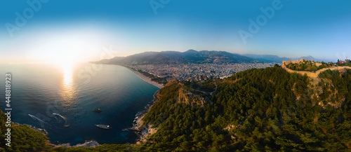 Large panorama. Wide aerial view from Kalesi Castle peninsula. Alanya, southern coast of Turkey, Summer sunset. Travel and vacation. Ships and boats in the mediterranean. Cleopatra beach and lake
