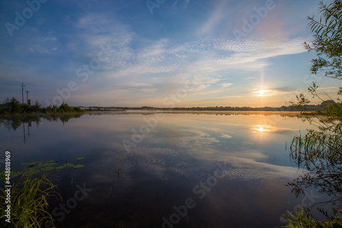 the bright blue sky at dawn is beautifully reflected in the mirror of the pond