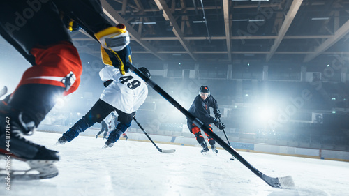 Ice Hockey Rink Arena: Professional Forward Player Attacks, Shows Expert Stickhandling, Dribbles, Handling Puck with Hockey Stick Beautifully, Defense Unable to Intercept. Low Angle View. photo