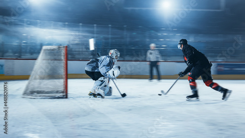 Ice Hockey Rink Arena: Goalie is Ready to Defend Score against Forward Player who Shoots Puck with Stick. Forwarder against Goaltender One on One. Tension Moment with Blurred Motion.