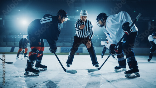 Ice Hockey Rink Arena Game Start: Two Players Brutal Face off, Sticks Ready, Referee is Going to Drop the Puck, Athletes Ready to Fight. Intense Game Wide of Energy Competition, Speed. photo