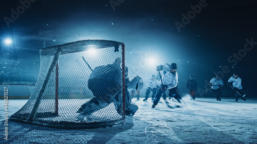 Ice Hockey Rink Arena: Goalie against Forward Player who Does Slapshot, Shots Puck with Stick and Scores Goal. Forwarder against Goaltender. photo
