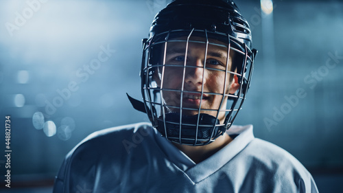 Ice Hockey Arena: Portrait of Confident Professional Player, Wearing Wire Cage Face Mask, Looking at Camera and Smiling. Close-up Shot