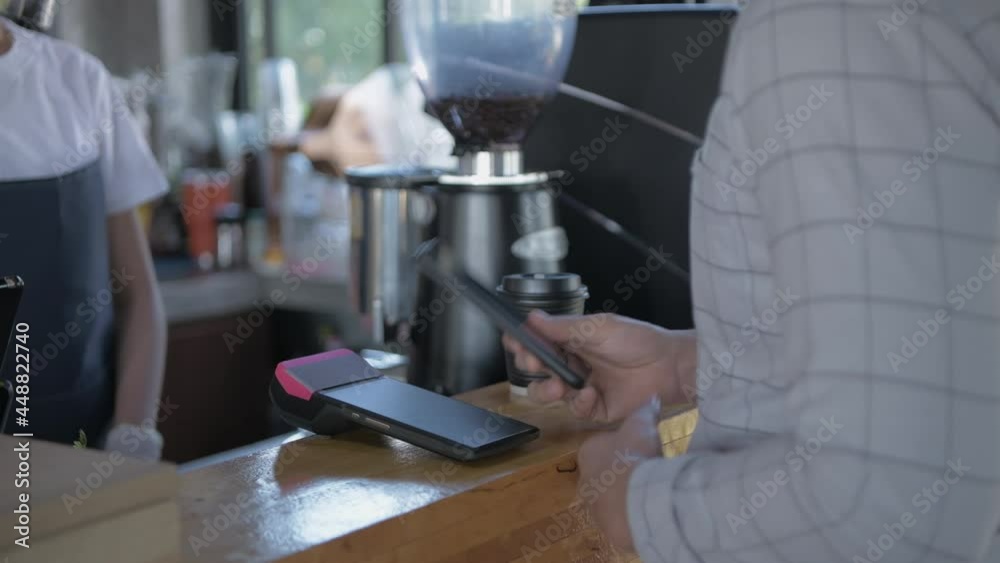 Coffee shop concept of 4k Resolution. The employee is handing the payment machine to the customer for scanning.
