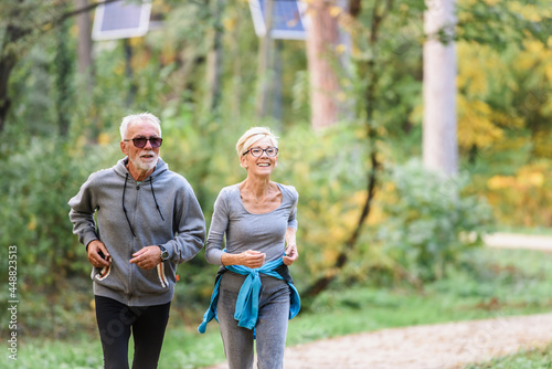 Fototapeta Naklejka Na Ścianę i Meble -  Smiling senior couple jogging in the park. Sports activities for elderly people.