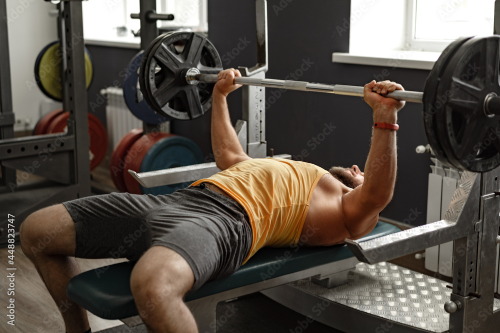 Bearded man bodybuilder doing bench press exercise in gym Bearded man bodybuilder doing bench press exercise in gym