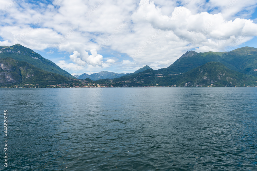 Beautiful view over the stunning lake Como in Lombardy, Italy. It is a very nice sunny summer day, with blue sky and a few white clouds. View is from the harbour in the city of Varenna
