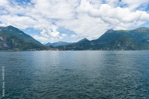 Beautiful view over the stunning lake Como in Lombardy, Italy. It is a very nice sunny summer day, with blue sky and a few white clouds. View is from the harbour in the city of Varenna